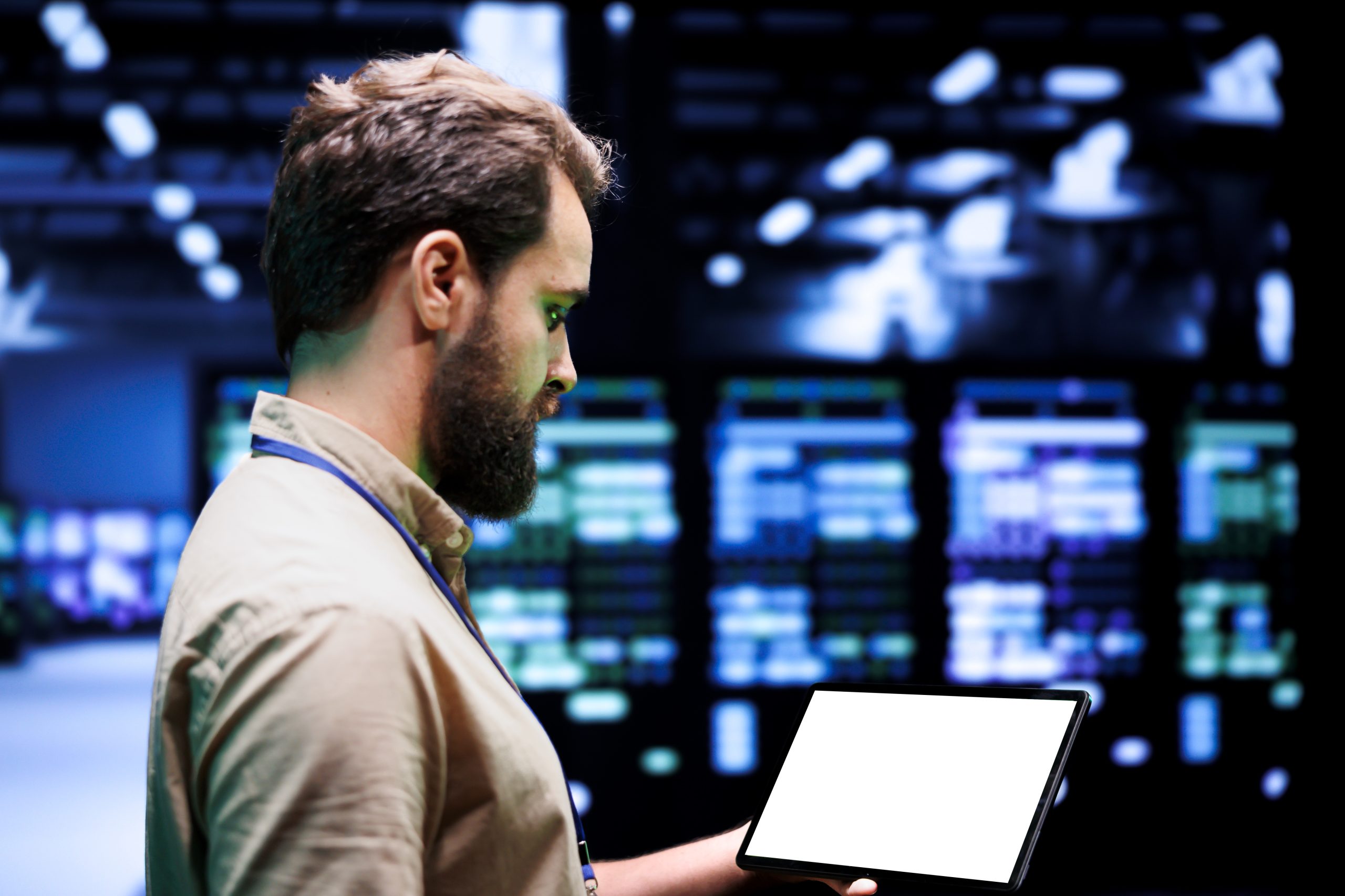 A man holding a laptop in a computer or server room.